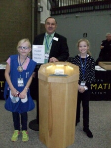two young numismatists and a man at a display case